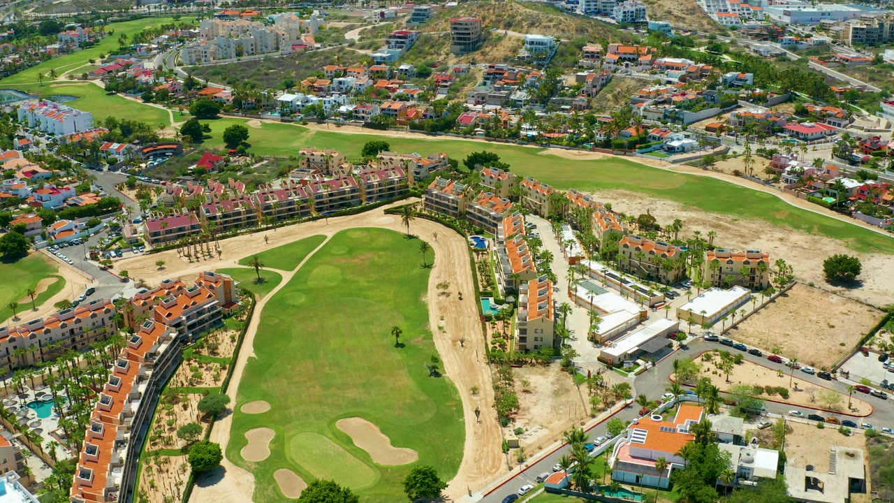 Drone view over golf fairway, apartment blocks, roads, and dry terrain