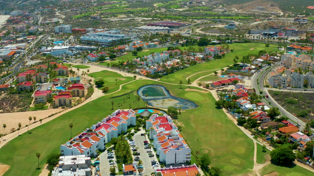 Aerial view across a golf course and residential blocks with distant hills.