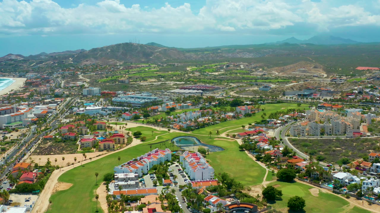 Aerial view of golf course and coastal resort development under clouds.