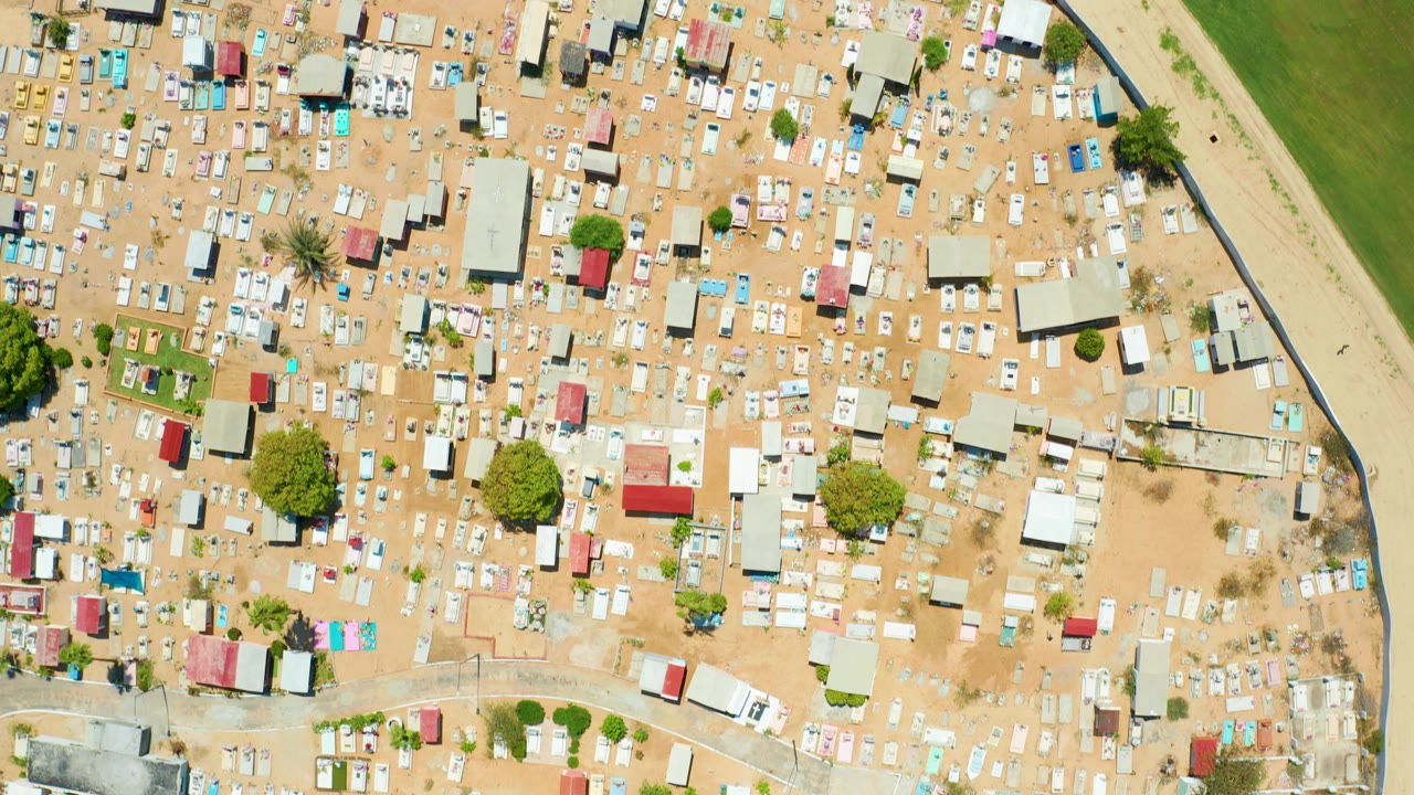 Top-down view of a dense sandy settlement with scattered trees and small buildings.