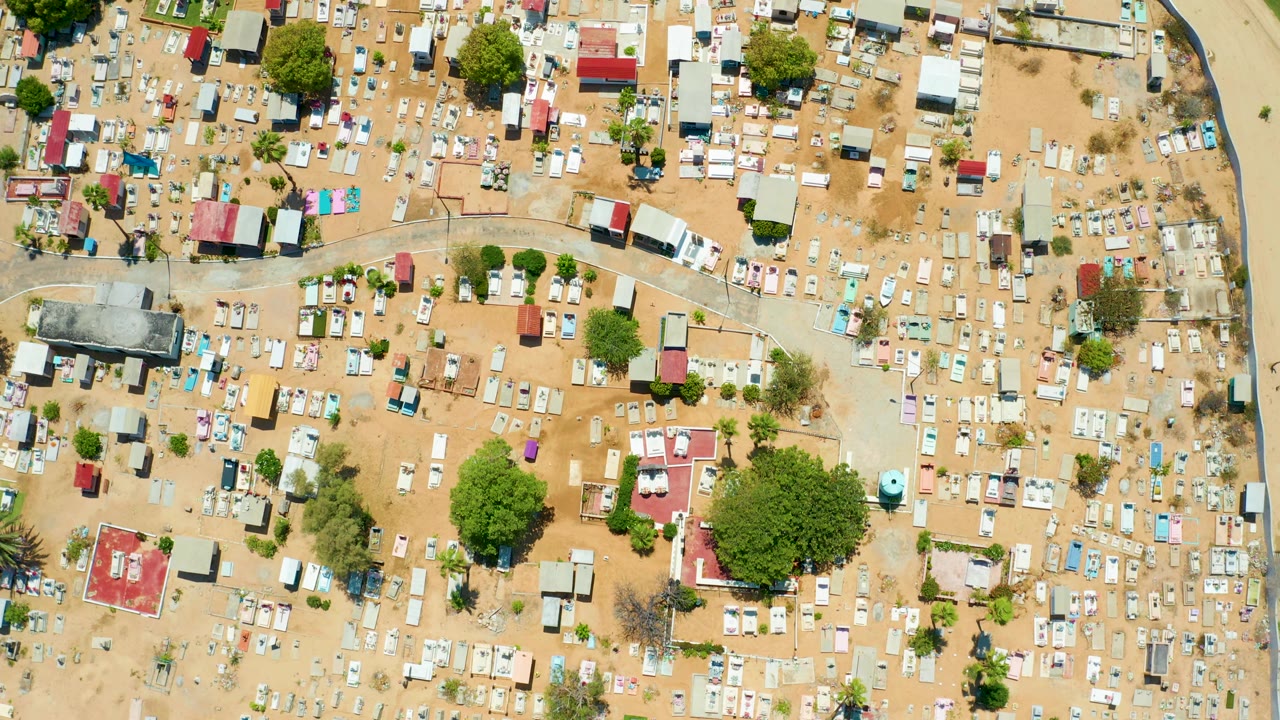 Overhead cemetery and settlement area with a curved road crossing sandy ground.