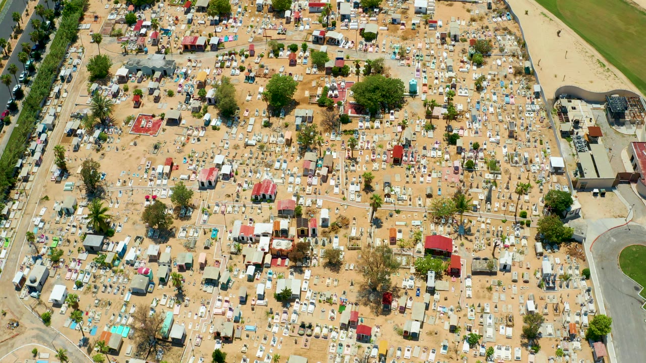 Top-down view of a sandy mobile home and RV area bordered by trees and roadways.