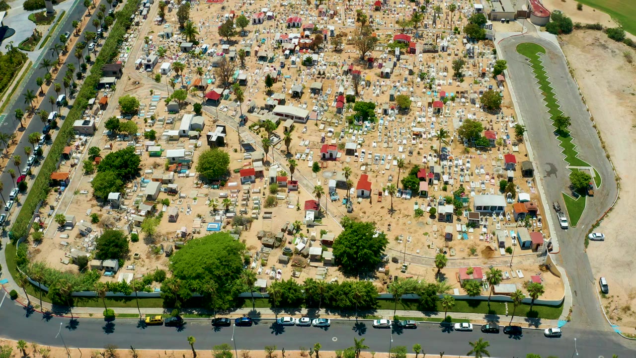 Overhead view of tents and small structures across a sandy lot.
