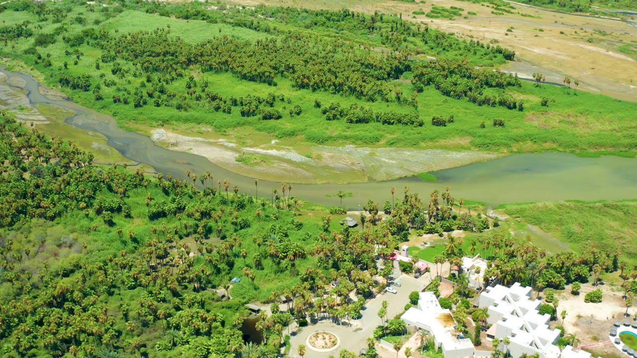 Aerial landscape with river water, green banks, trees, and resort grounds below.