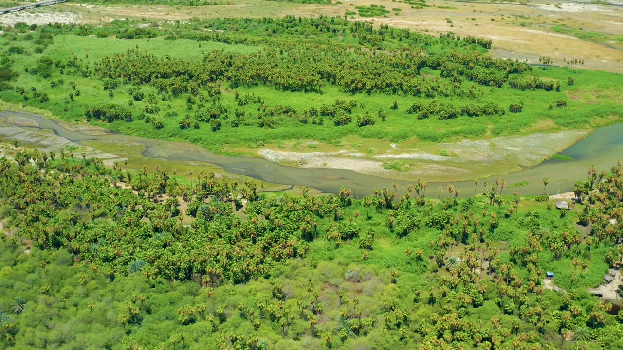 High aerial view of green riverbanks and a shallow curving water channel.