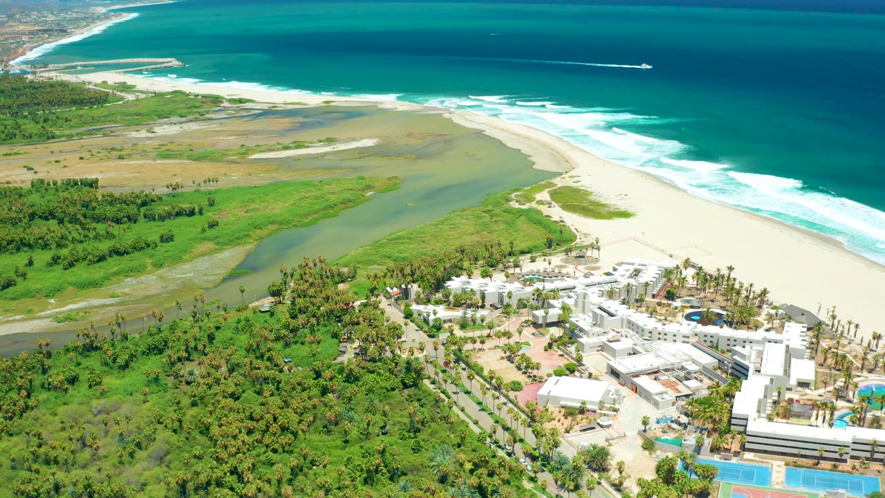 Coastal wetland, sandy beach, ocean surf, and resort buildings from above.