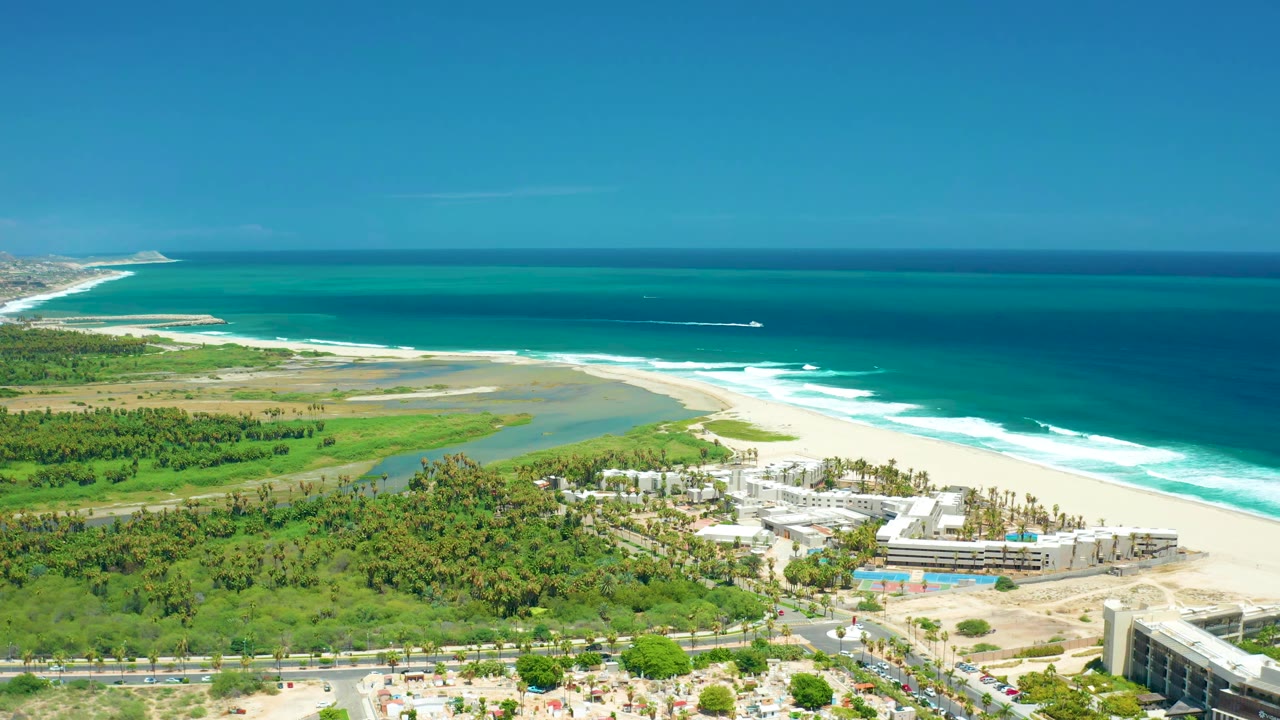 Wide aerial shoreline with boat offshore and resort buildings below.