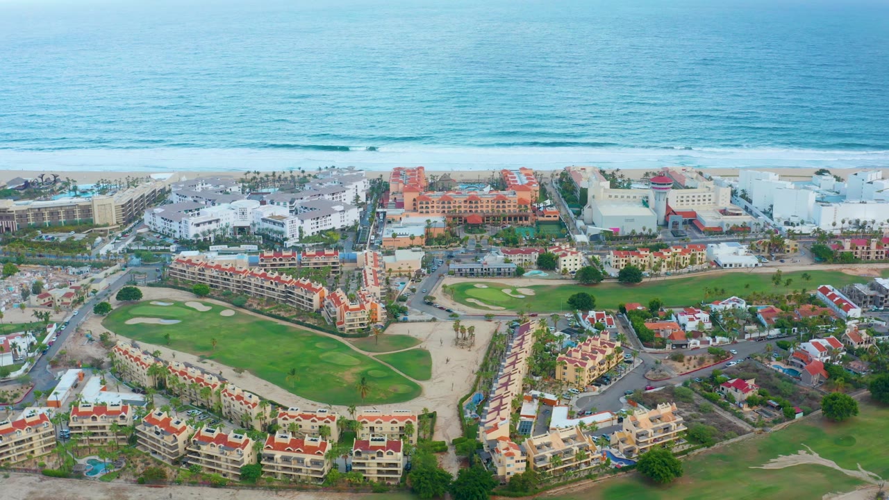 Coastal residential buildings beside a golf course and ocean.