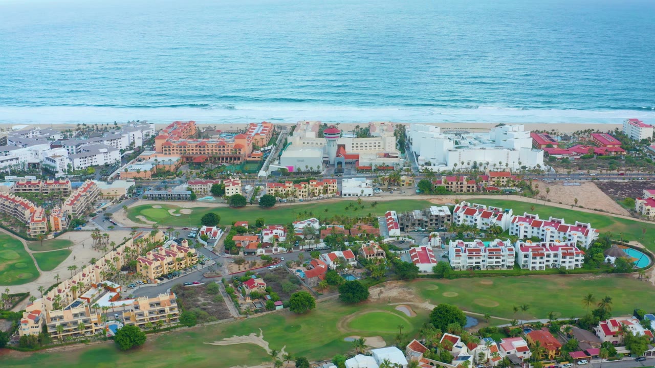 Drone view of residential blocks beside a beach and ocean.