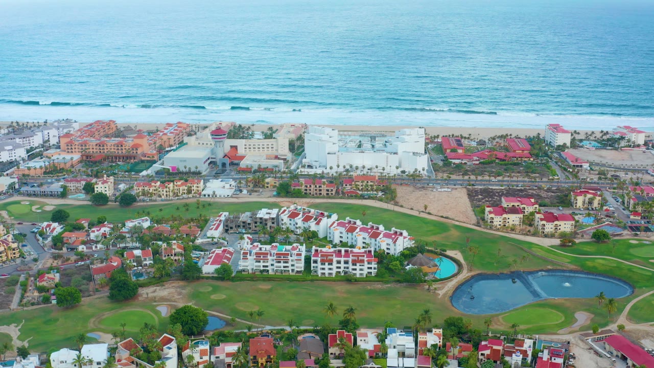 Beachfront resort district with ocean waves, roads, lawns, and ponds.