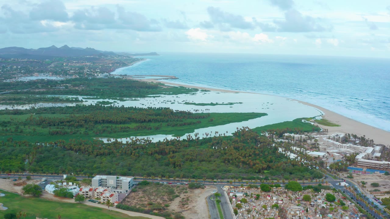 Aerial view of lagoon, beach, ocean, roads, buildings, and distant hills.