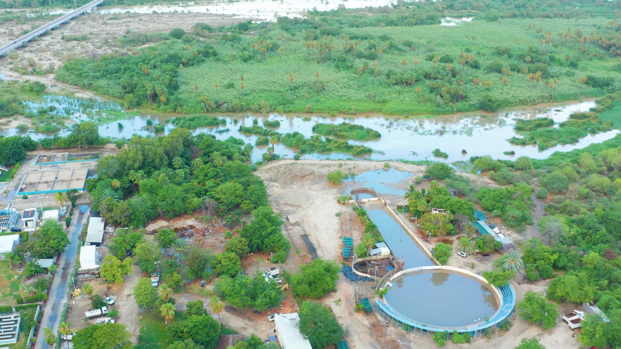 Aerial view with circular tank in the lower foreground and river vegetation across the top.