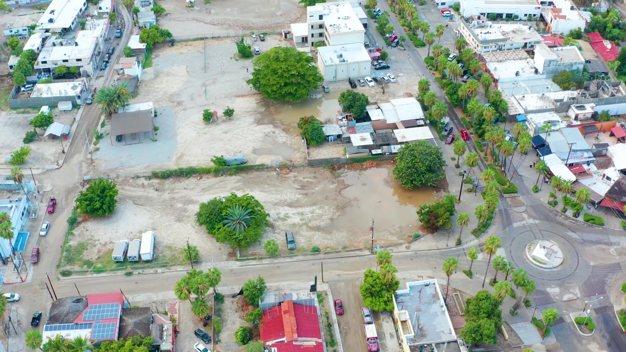 Overhead neighborhood view with floodwater in an open lot by a roundabout.