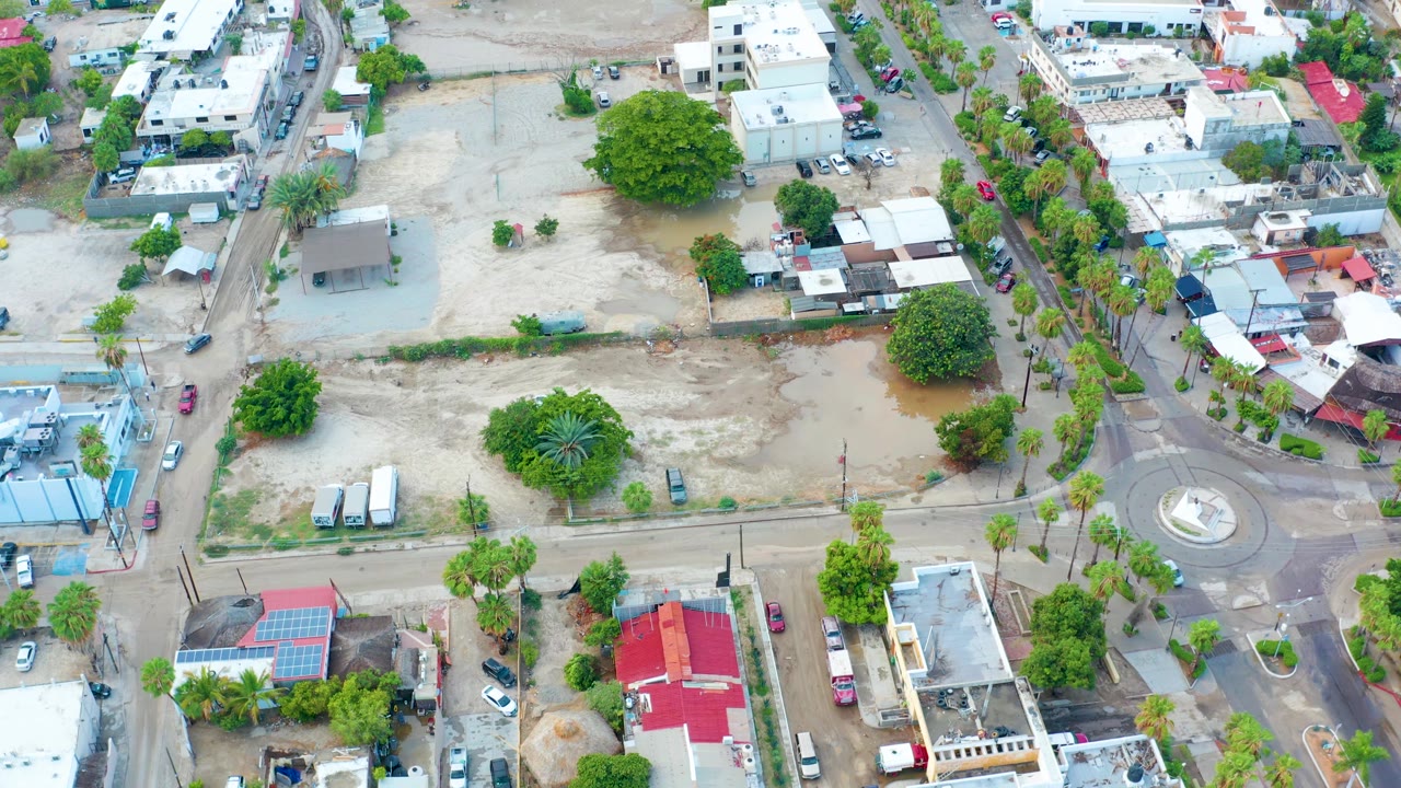High aerial view of residential blocks around a flooded dirt area.