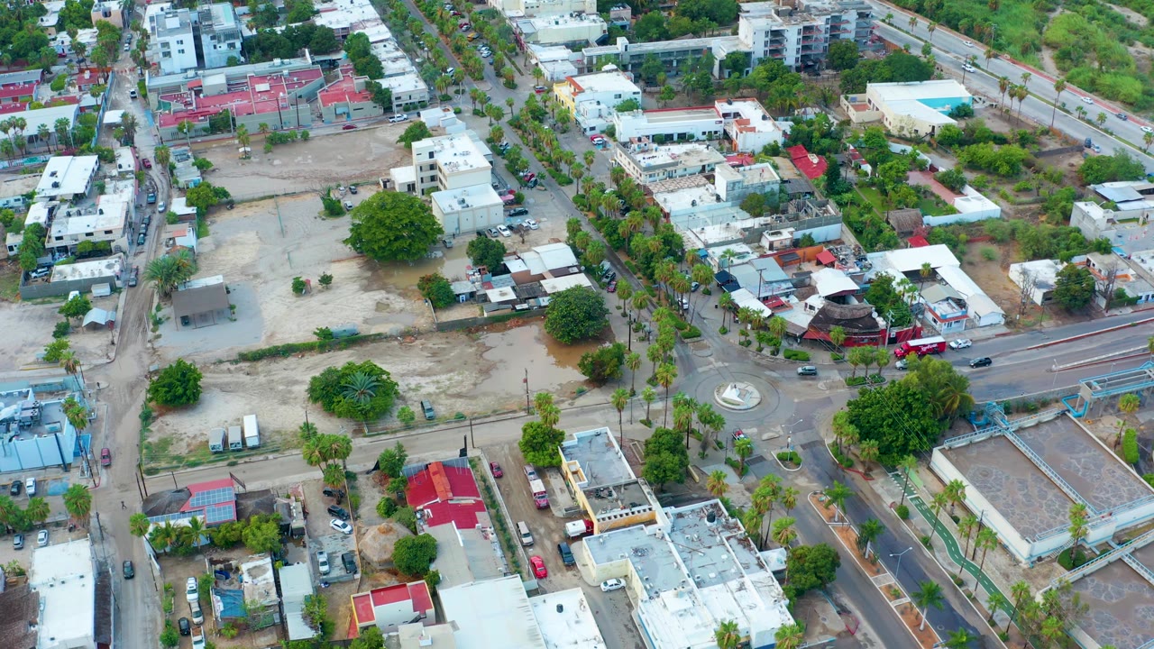 Drone view of residential blocks, roads, trees, and a small roundabout.