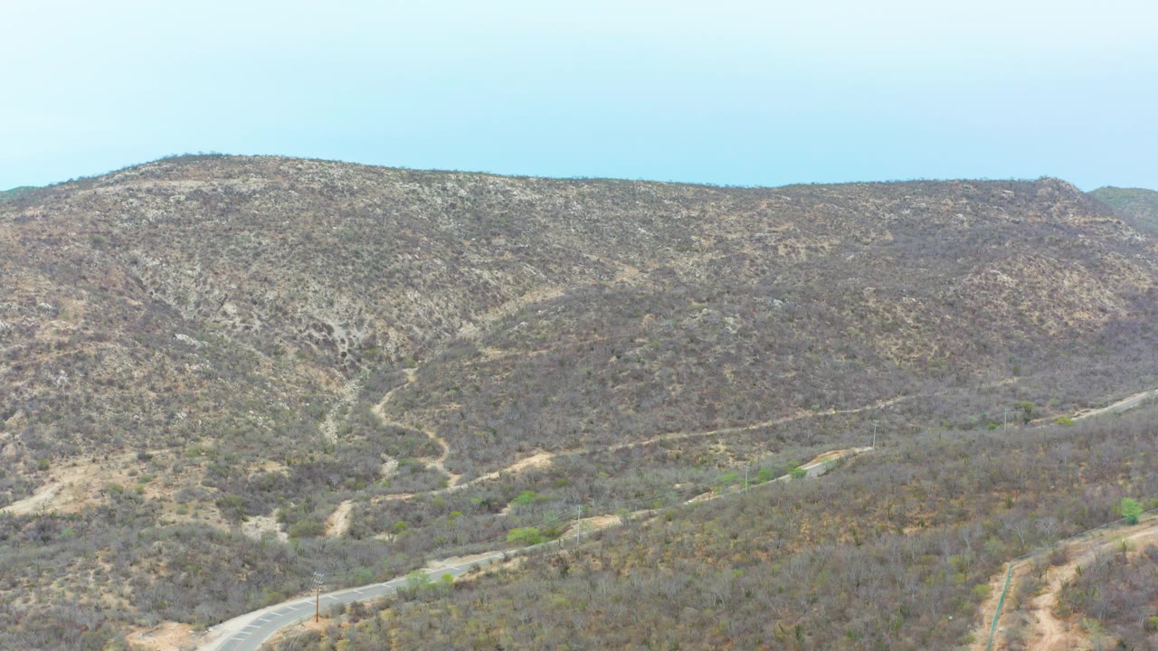 Aerial view of dry hills and a winding paved road