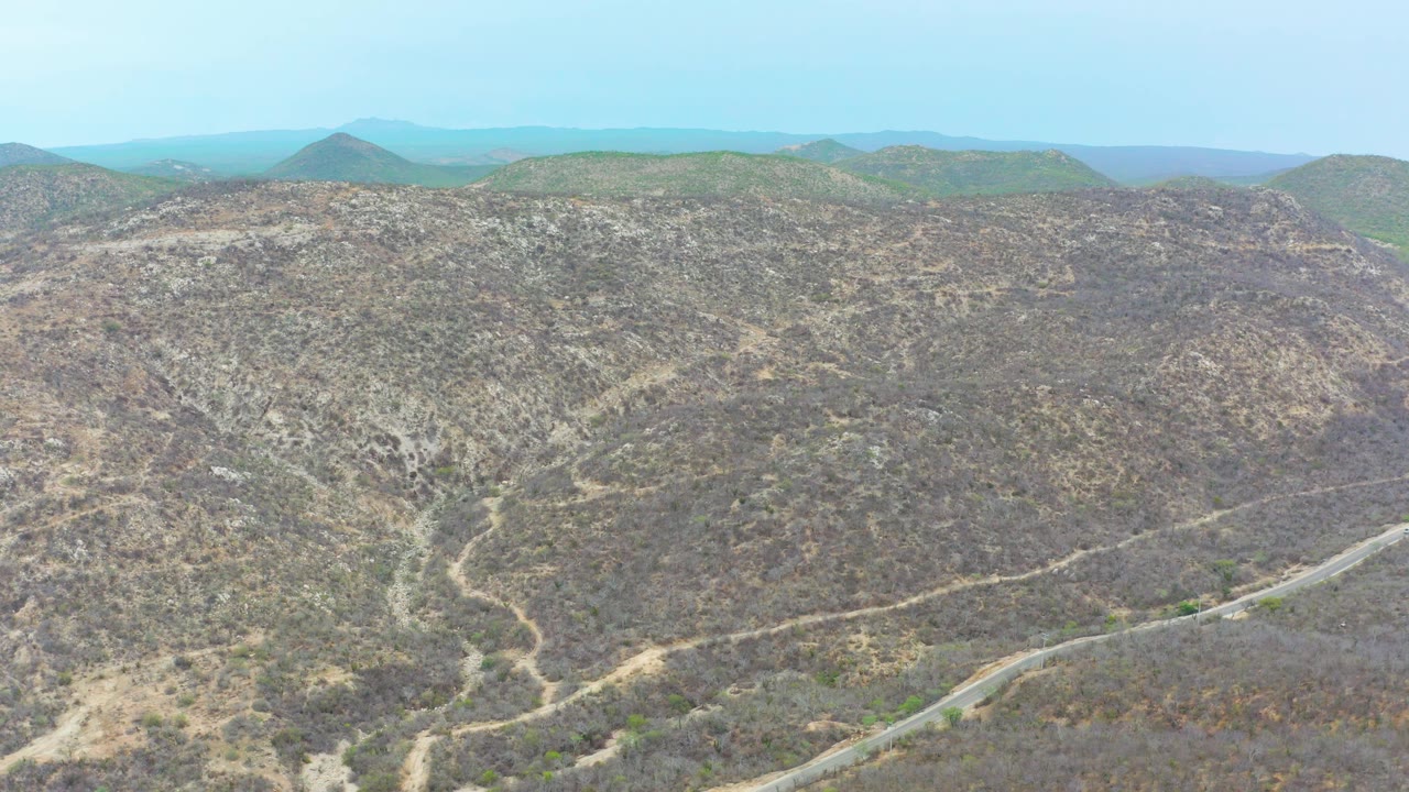 Dry hilly landscape with pale dirt tracks and a road near the bottom right.