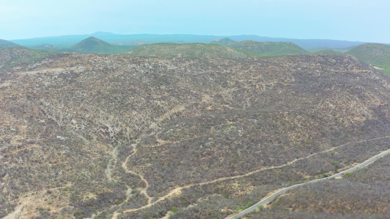 Dry hilly terrain with road along the lower frame and rounded hills beyond.