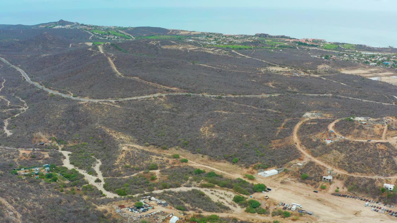 High aerial view of dry hills, winding tracks, and scattered structures.
