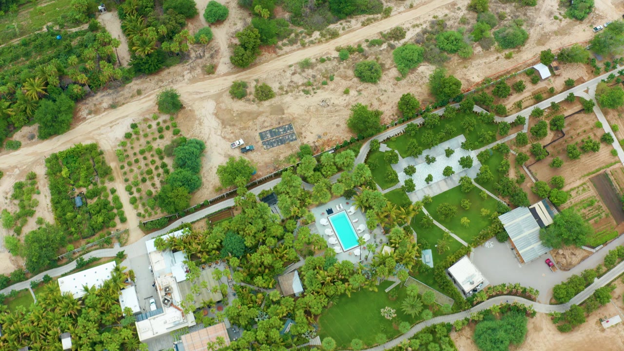 White vehicle on a dusty road above walled gardens and a pool.