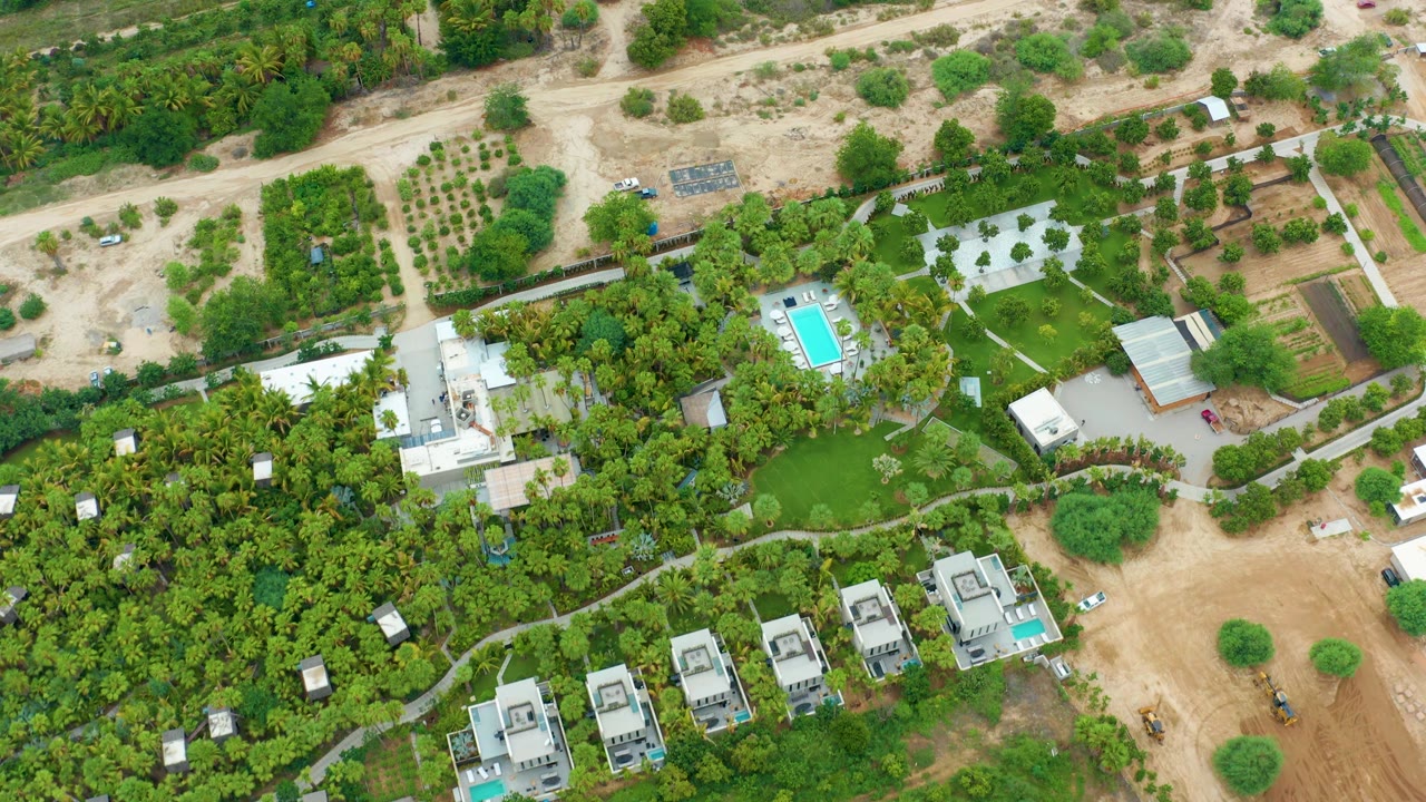 High aerial view of green residential grounds, dirt access roads, and construction lots.