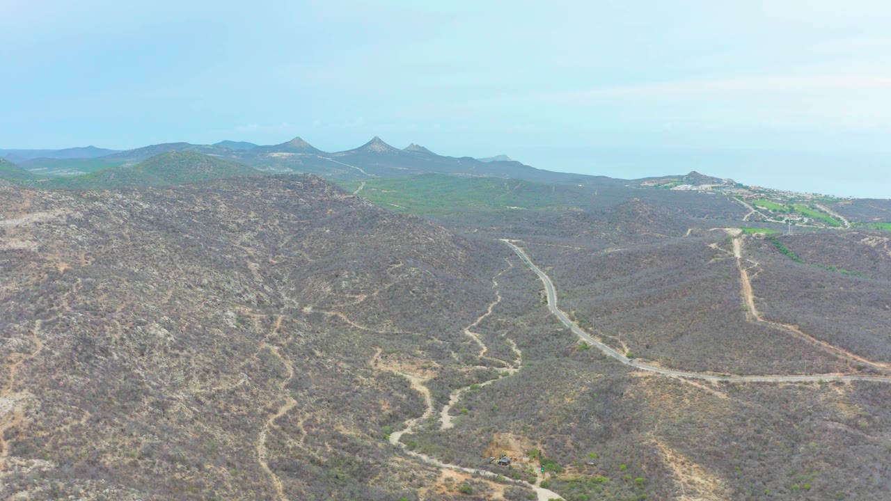 Aerial mountain road curving through sparse desert vegetation.
