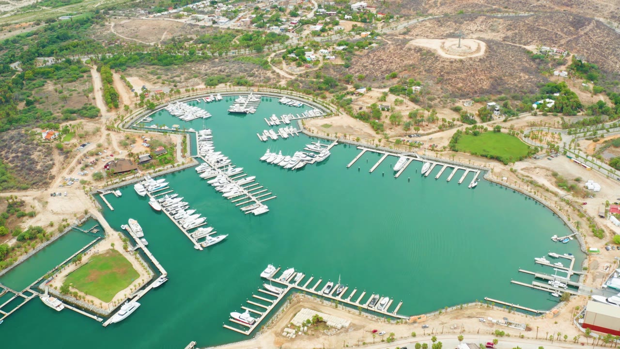 Aerial view of marina docks beside a square green shoreline enclosure.