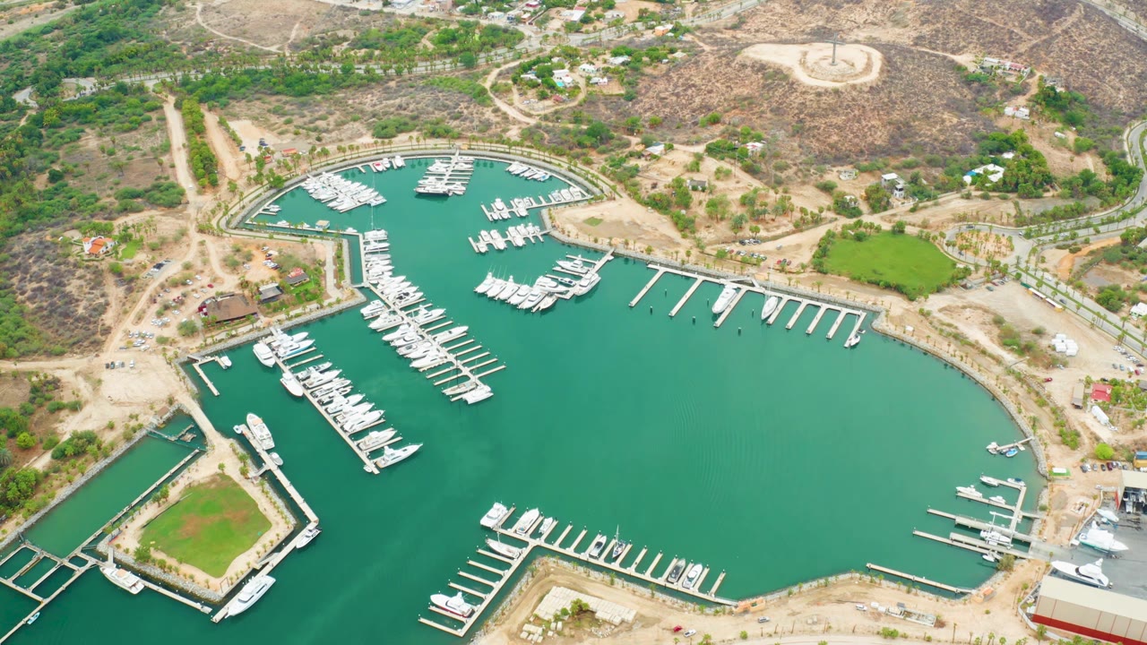 Aerial marina view with a rectangular dock area, boats, and green water.