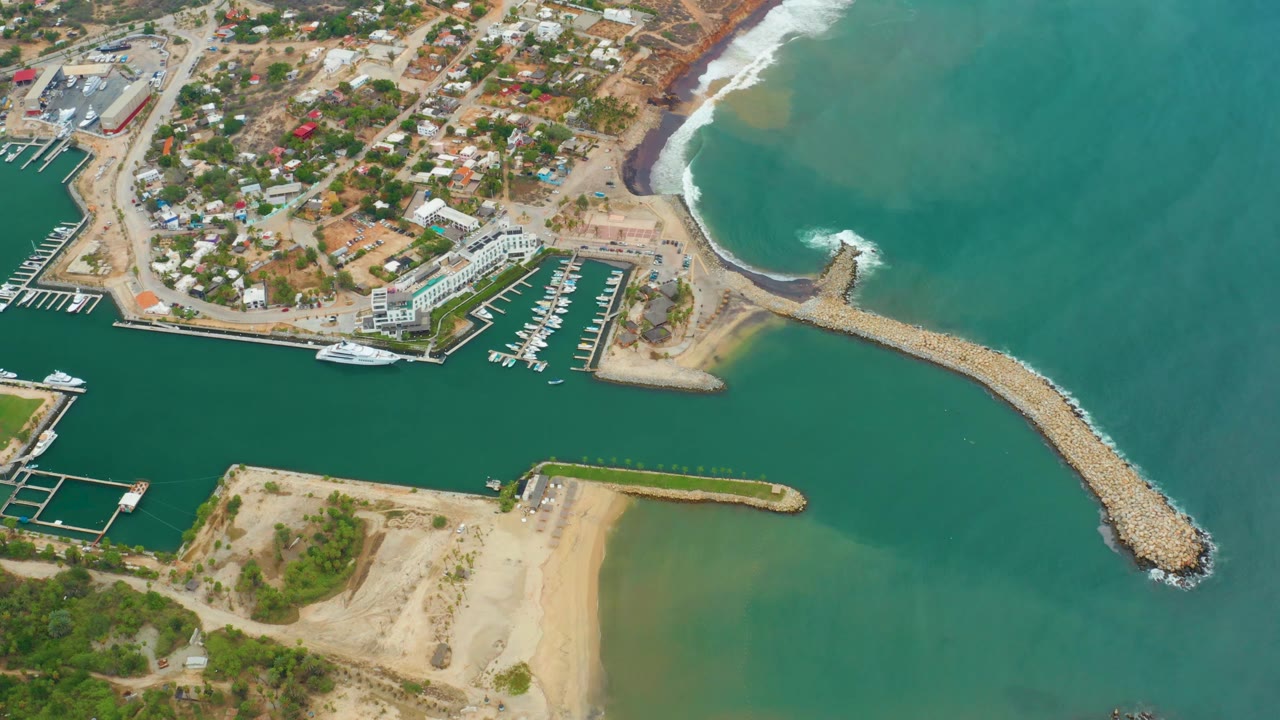 Aerial coastline with marina docks, beach, and surf on rocks
