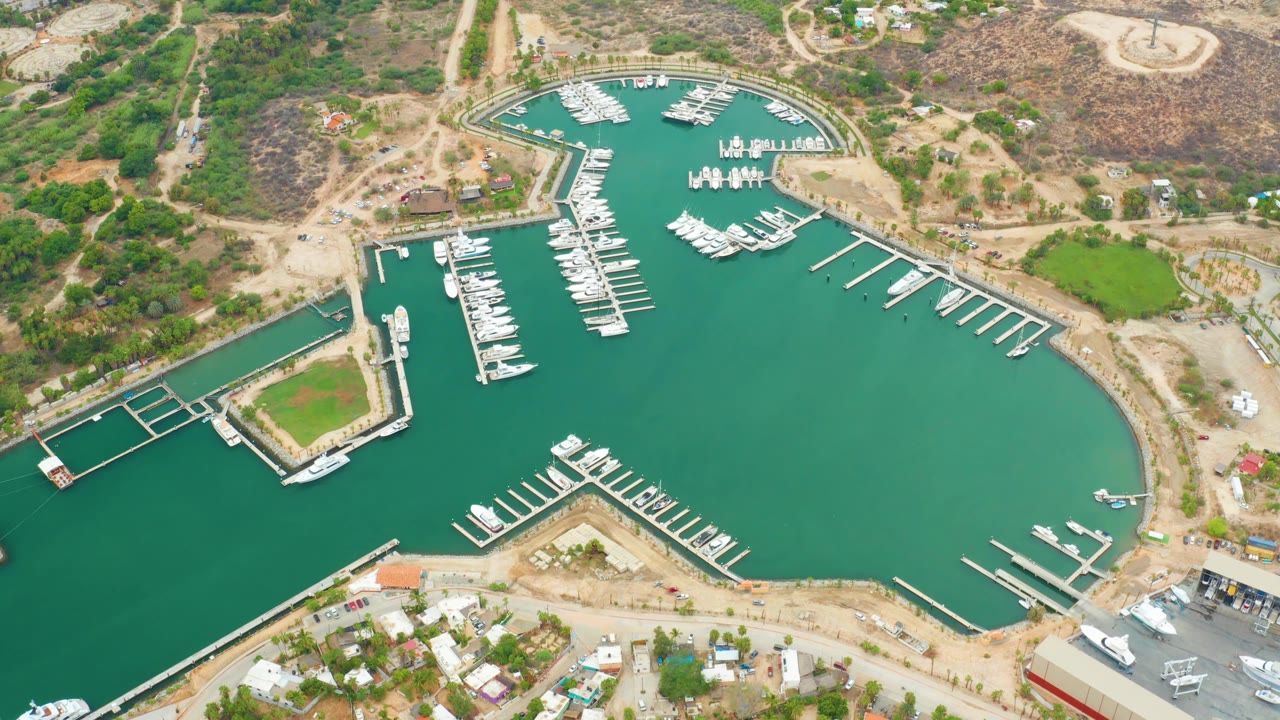 Aerial marina basin with a docked boat near the lower edge and hills beyond the slips.