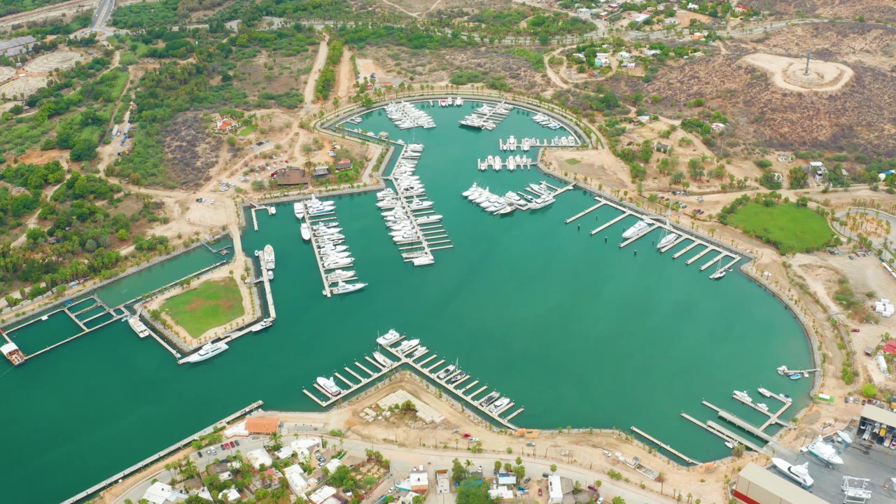Aerial harbor view with boats at slips, piers, green water, and dry terrain.