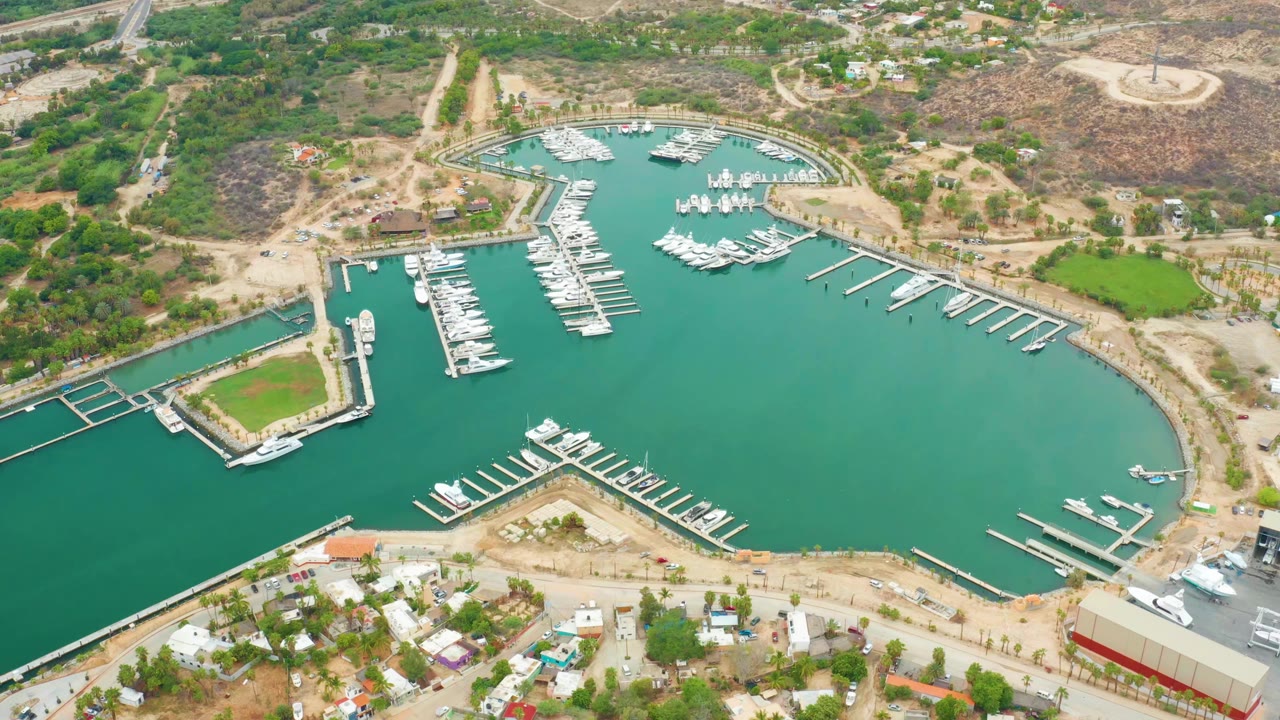 High aerial view of marina slips and boats in calm green water beside dry land.