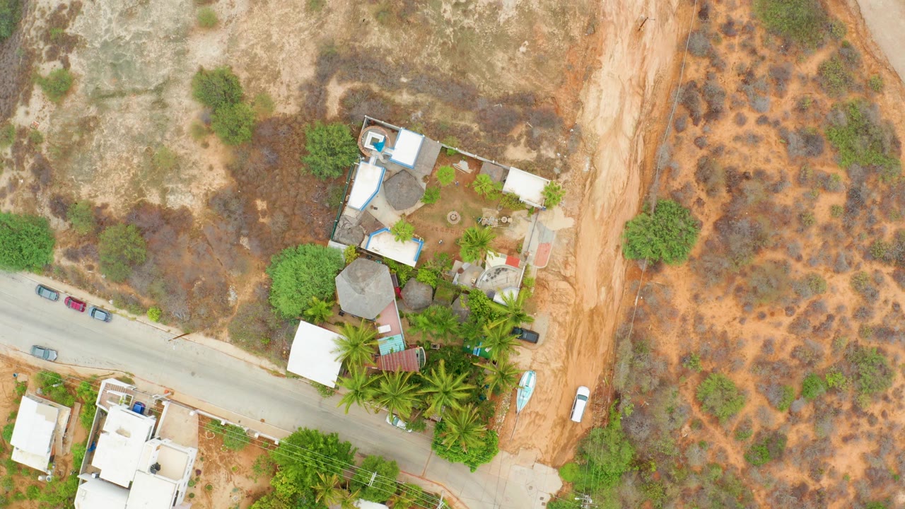 Overhead view of a roadside compound and dry hillslope vegetation.