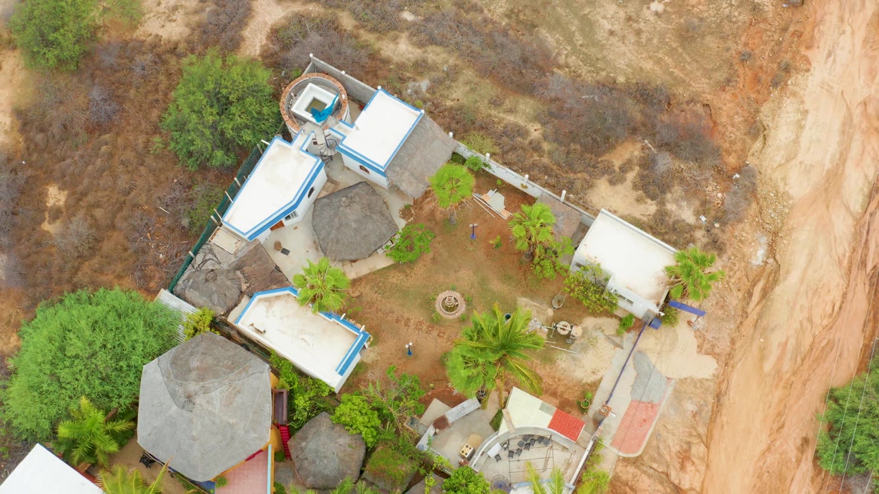 Overhead view of white and thatched roofs in dry terrain.