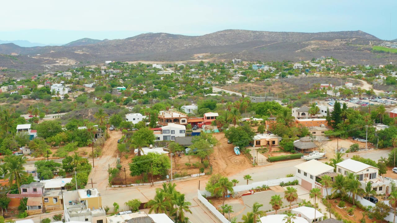 Residential aerial with dirt roads, scattered houses, and hills