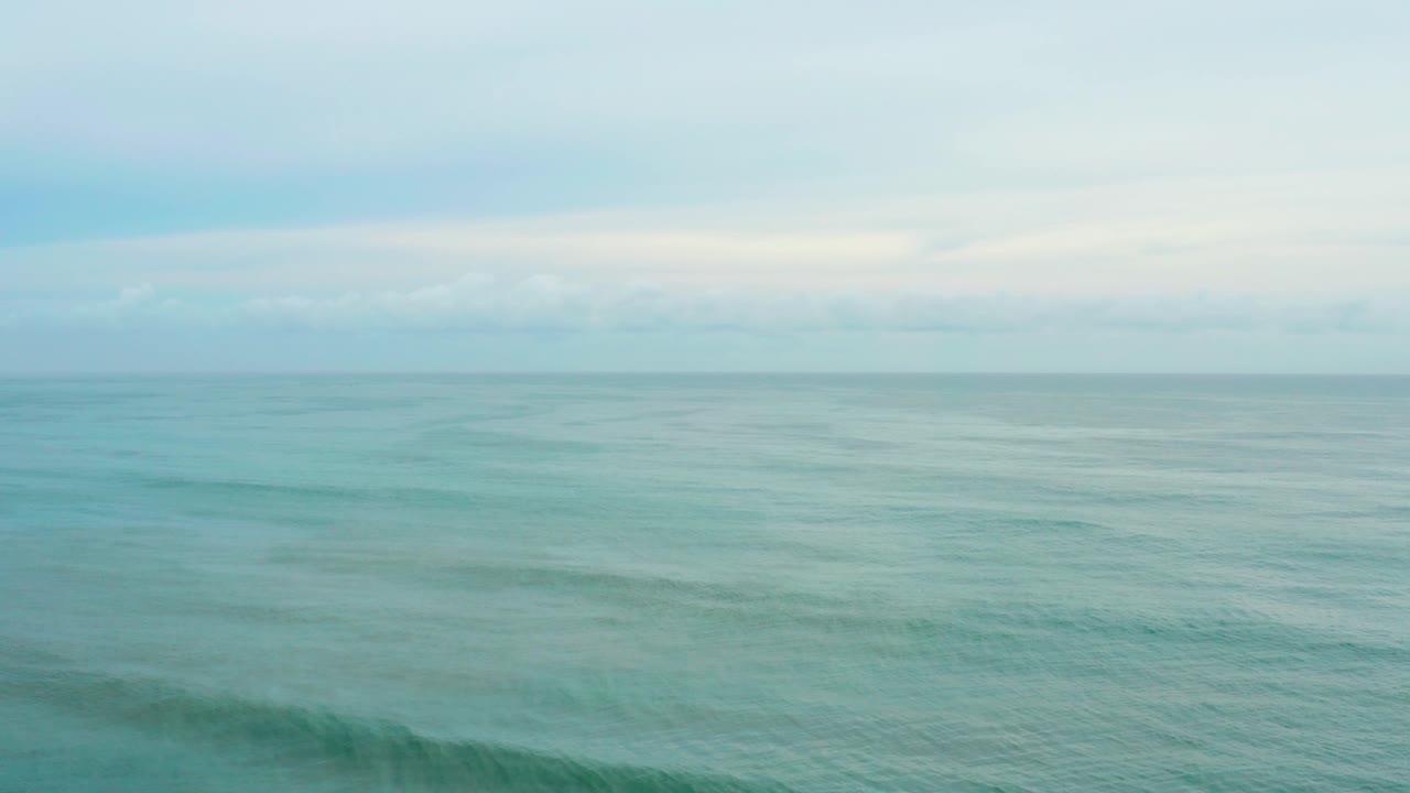 Mid-clip frame of La Playita Los Cabos ocean water with subtle turquoise variation, a thin horizon line, overcast sky, and no visible people.