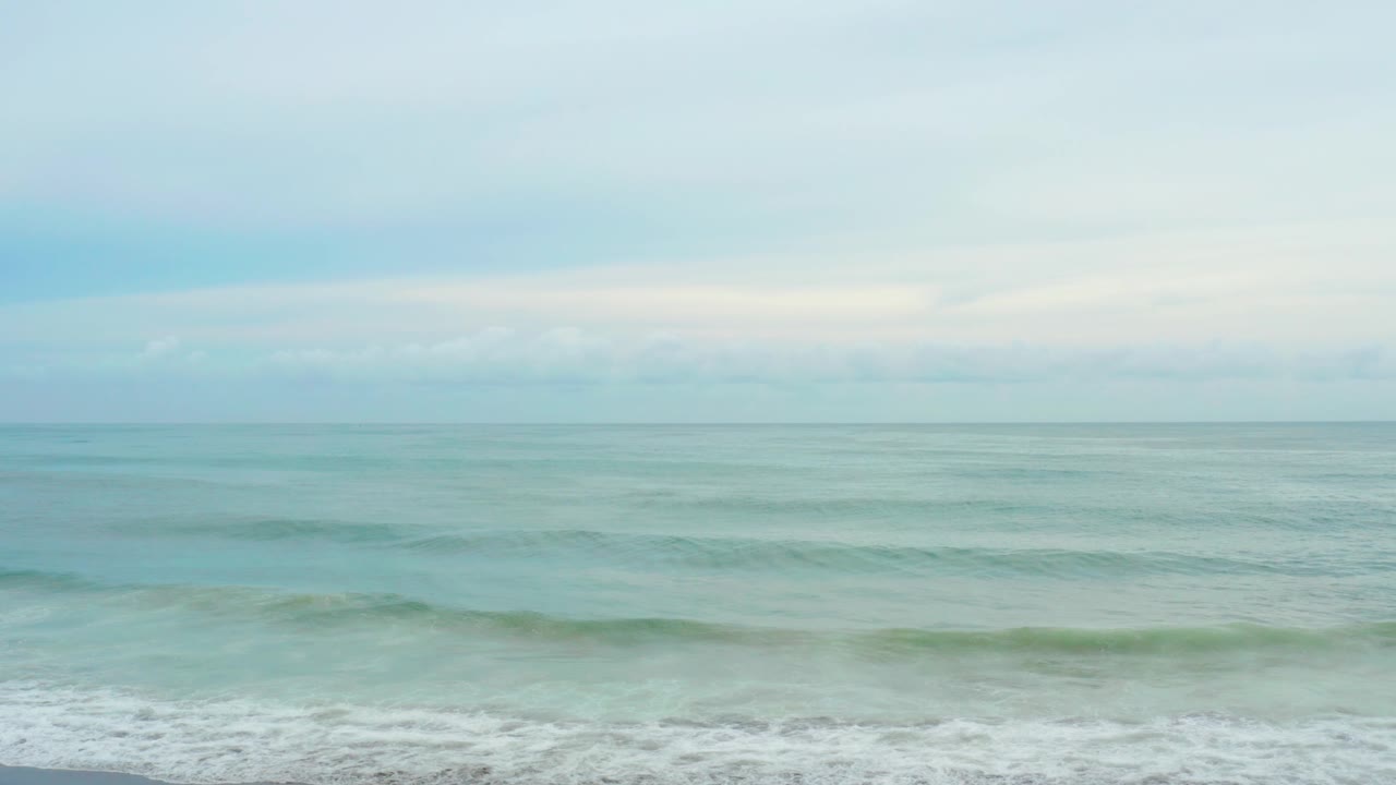 At La Playita Los Cabos, a low green-blue swell gathers across the middle of the frame while white wash stays along the bottom, with no visible people.