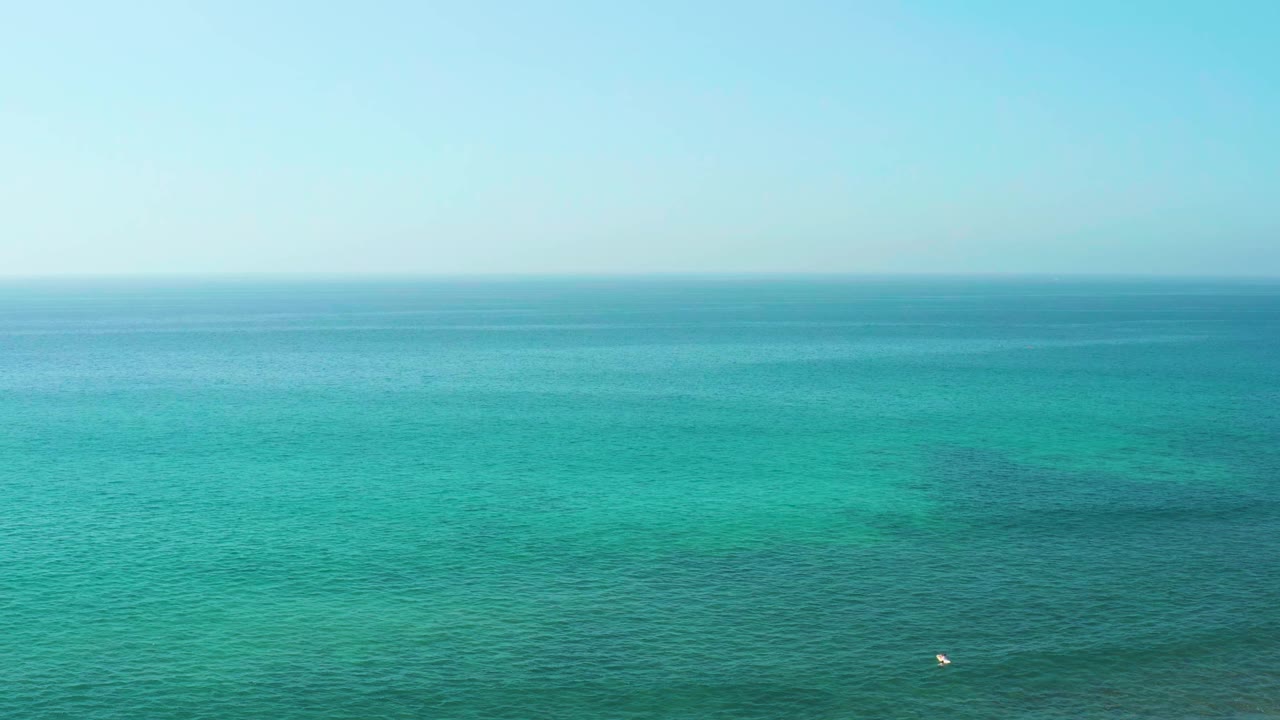 Second frame shows the El Tule Beach ocean horizon held high over textured turquoise water, with the small white buoy slightly right of lower center and no visible people.
