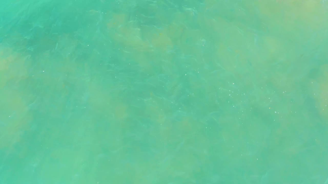 Clear green-blue water over larger submerged rocks.