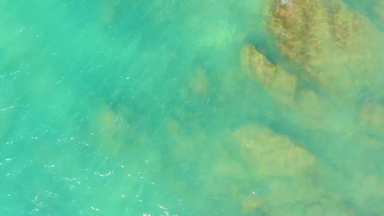 Turquoise water with rock cluster beneath