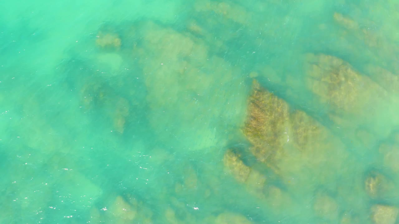 At three seconds, pale turquoise water softens the view of the rocks below, with a broad tan formation on the right and no visible people.