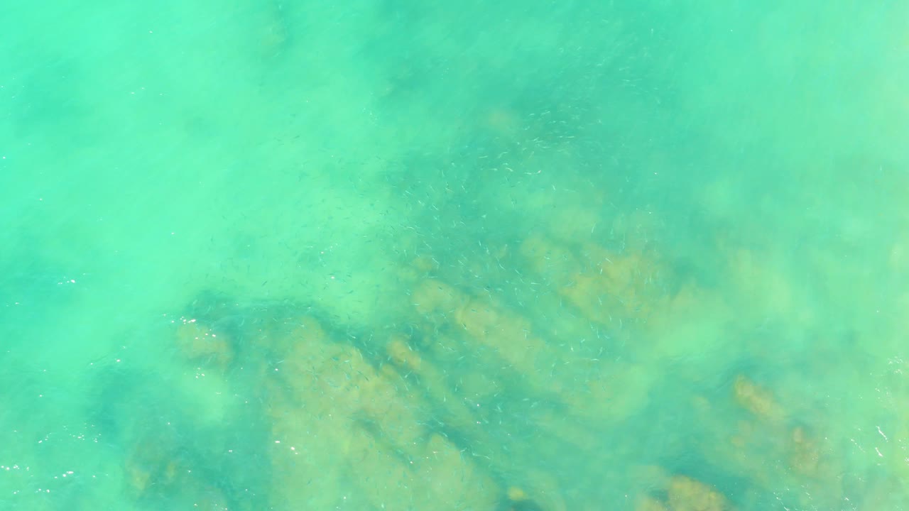 Turquoise ocean surface with submerged rock patterns