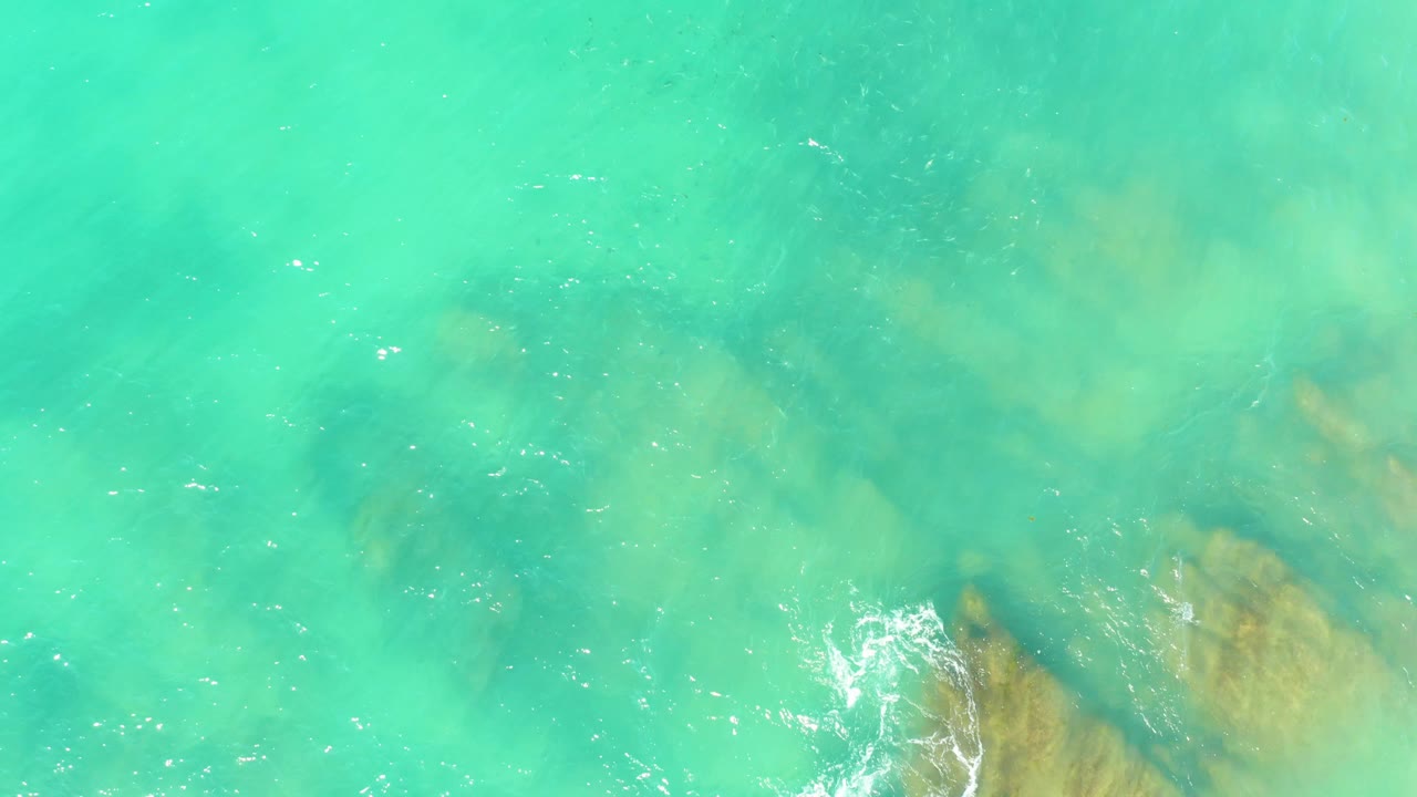 Clear turquoise water with rock shapes beneath the surface.
