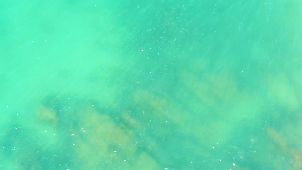 Turquoise shallow water with submerged rocks and light ripples.