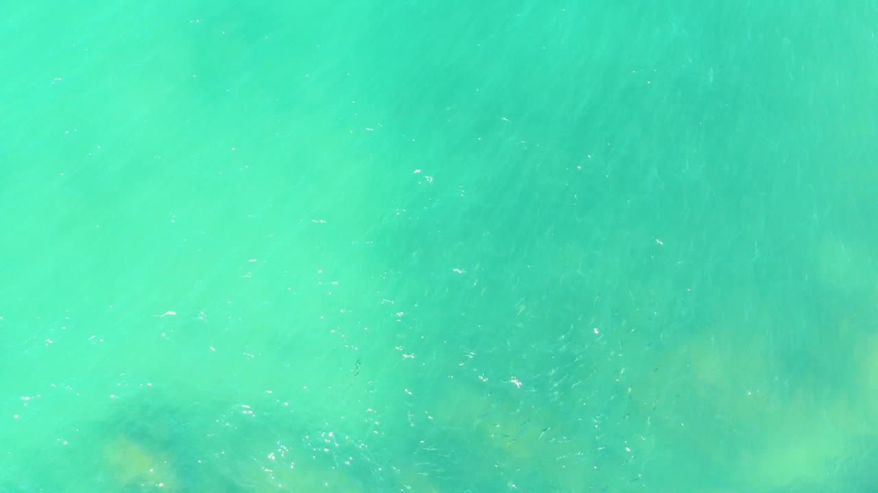 Turquoise water over faint submerged rocks