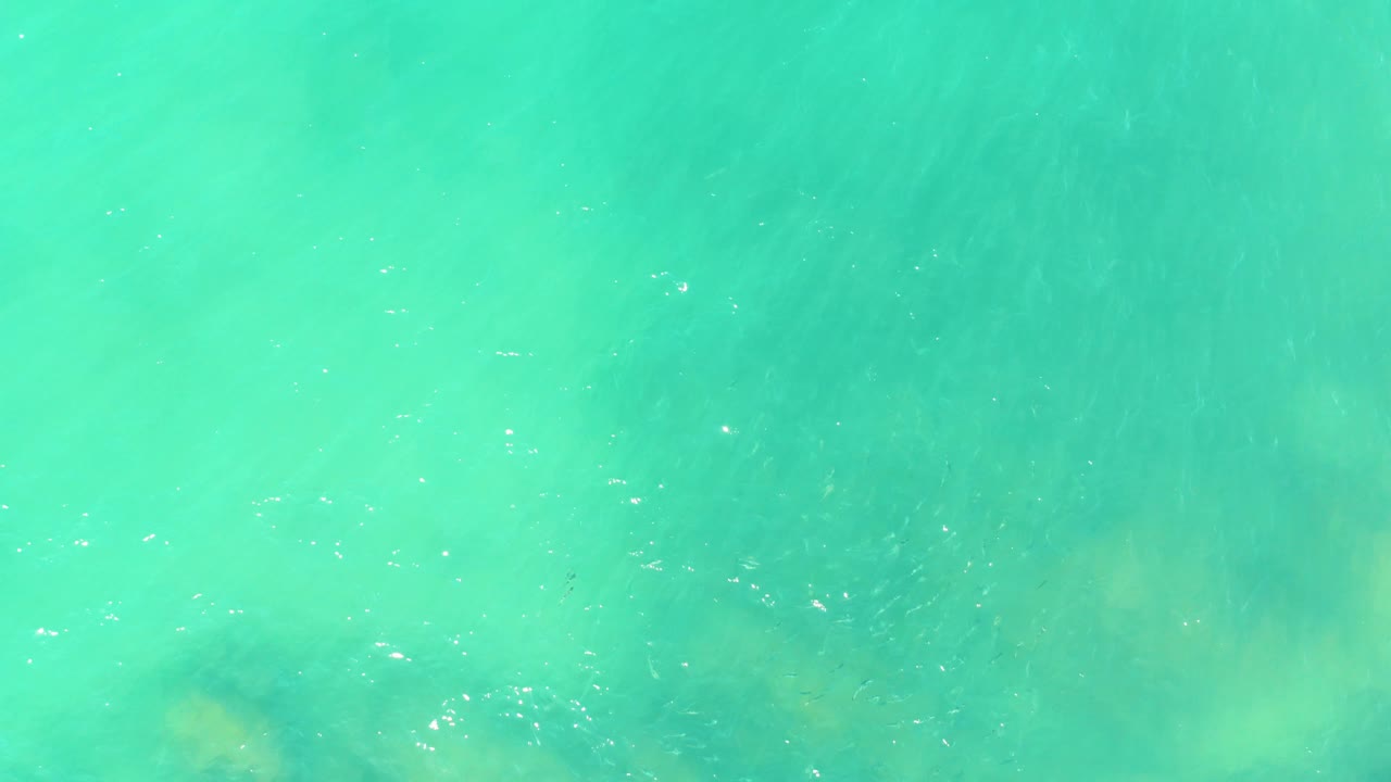 Rippling turquoise water at El Tule Beach in Los Cabos shows darker seabed patches beginning to appear through the surface, with no visible people.