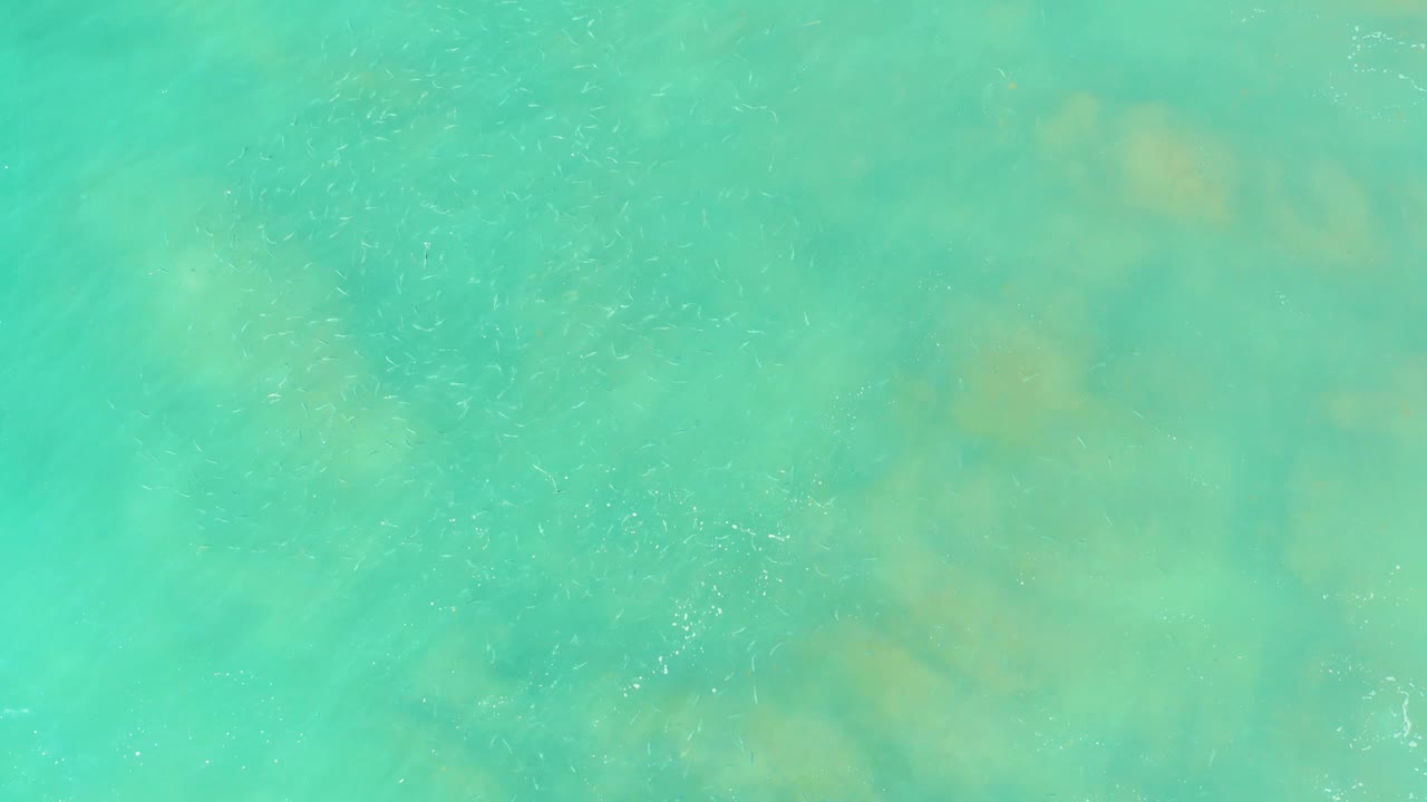 Aqua ocean surface at El Tule Beach in Los Cabos, showing soft ripple patterns over cloudy seabed shapes and no visible people.