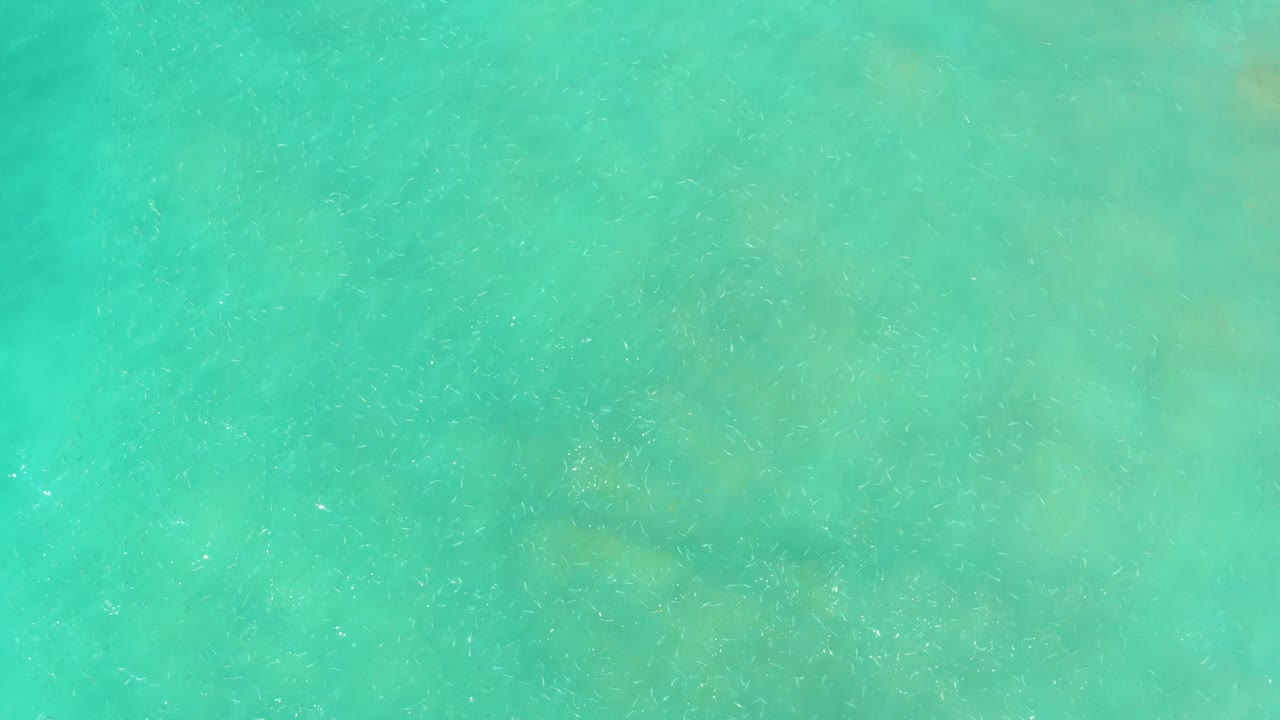 Turquoise ocean water at El Tule Beach Los Cabos shows subtle wave marks and pale-to-dark seabed color changes, no visible people.