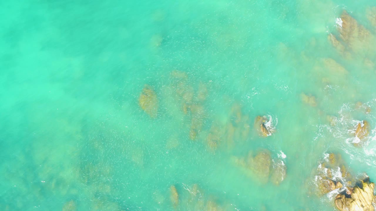 Overhead turquoise water with submerged rocks and small white wave breaks.