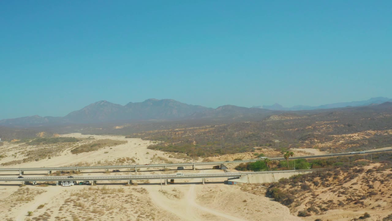 Highway overpass and sandy desert wash seen from above.